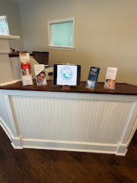Modern white reception desk at MerLeaux Aesthetics & Wellness Med Spa in Bay St. Louis, featuring check-in area and professional skincare displays.
